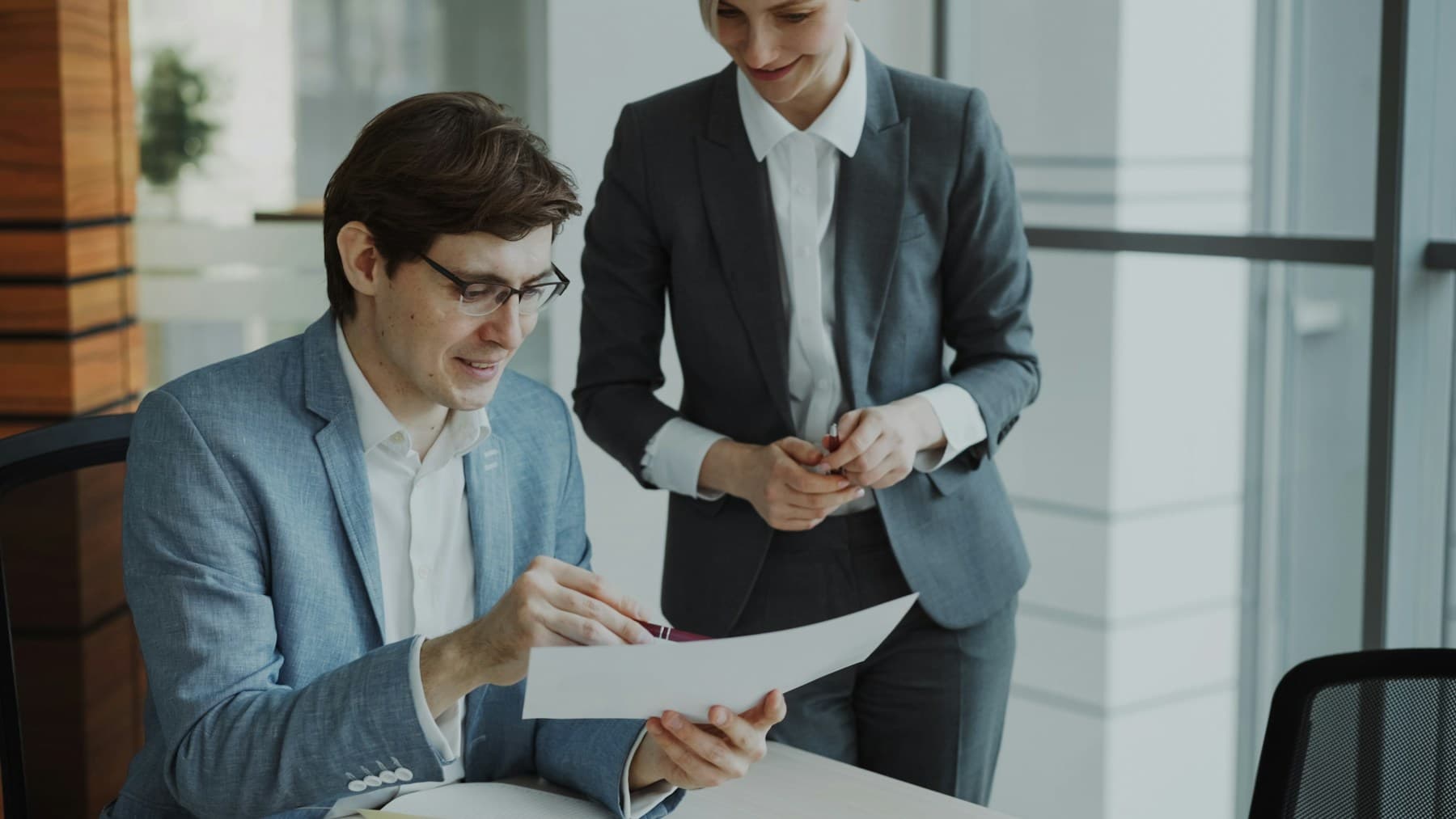 Two professionals reviewing a printed document together in an office.